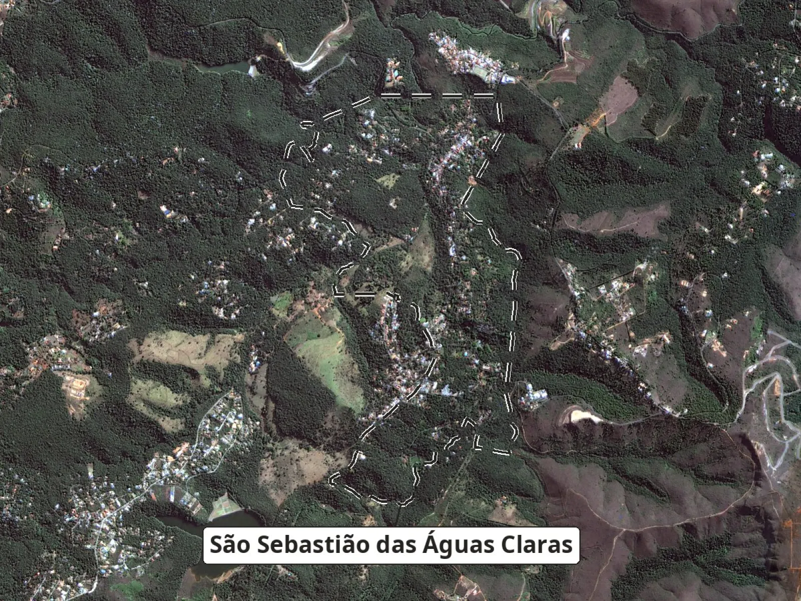 Imagem do satélite CBERS-4A de 23/07/2026 com o contorno de Macacos, as casas ao longo do vale central e do braço noroeste, mata no sul do bairro e um espelho d'água no canto sudoeste.